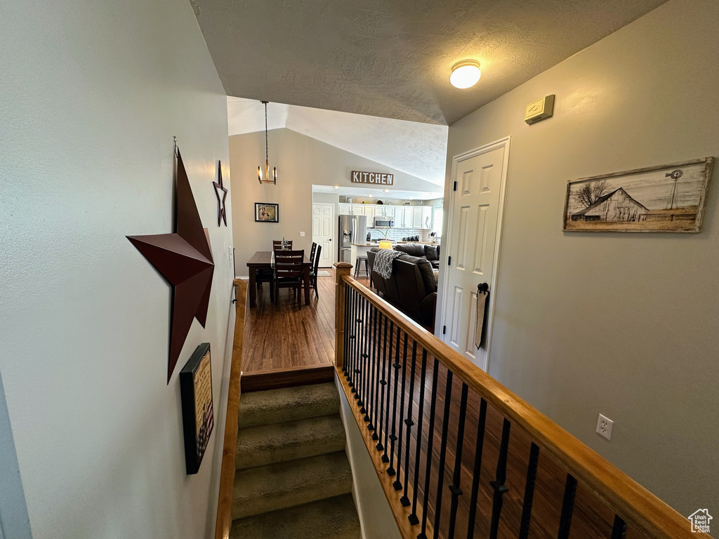 Stairs featuring wood finished floors and vaulted ceiling