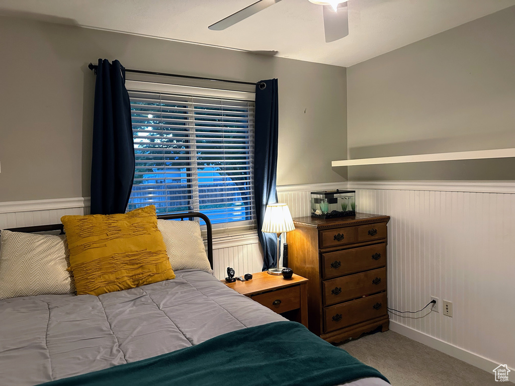 Carpeted bedroom featuring wainscoting and ceiling fan