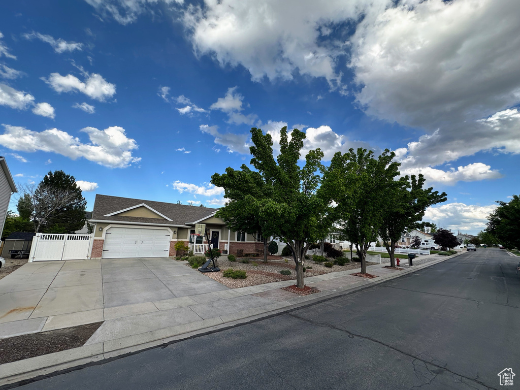 View of front facade featuring an attached garage, concrete driveway, brick siding, and a gate