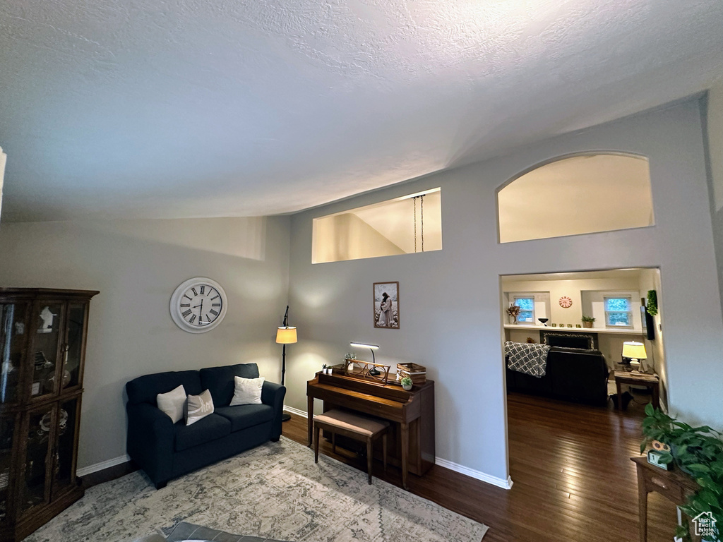 Living area with wood finished floors, lofted ceiling, and baseboards