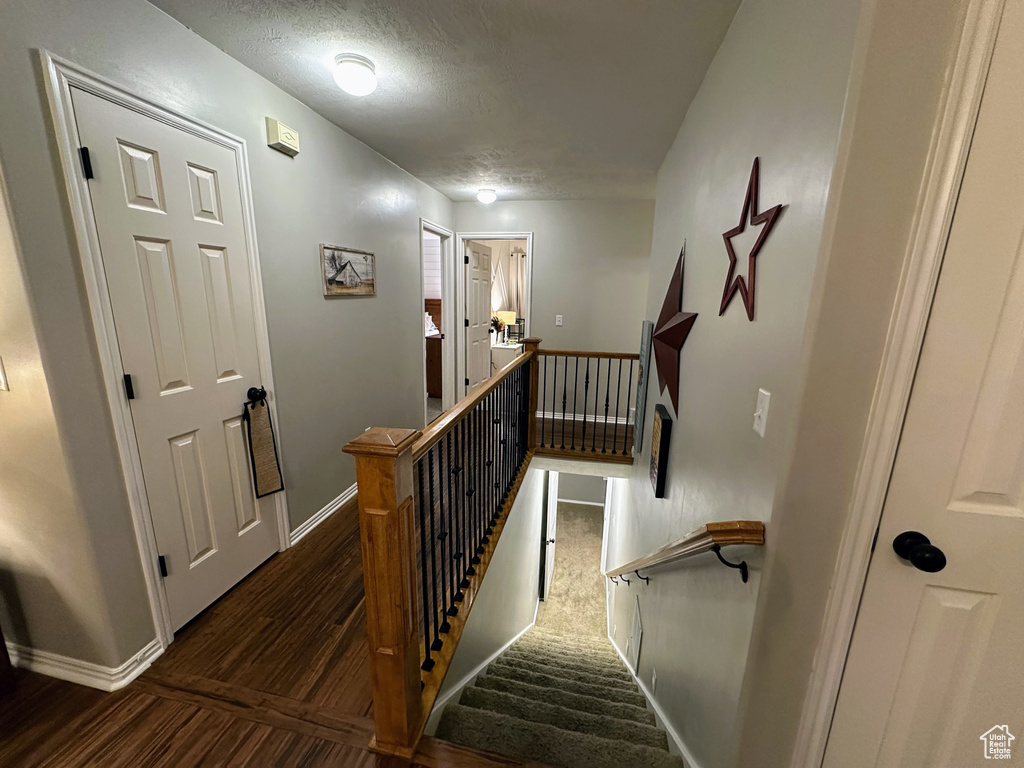 Stairs with baseboards, a textured ceiling, and wood finished floors