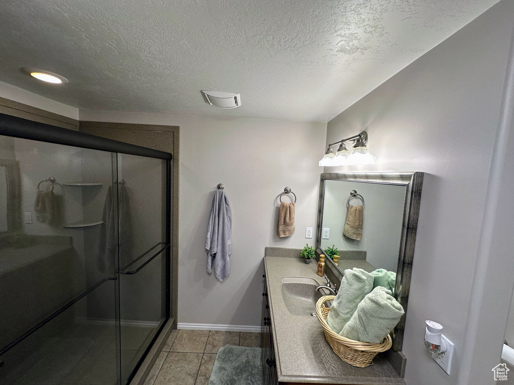 Full bathroom with vanity, a shower stall, baseboards, a textured ceiling, and tile patterned flooring