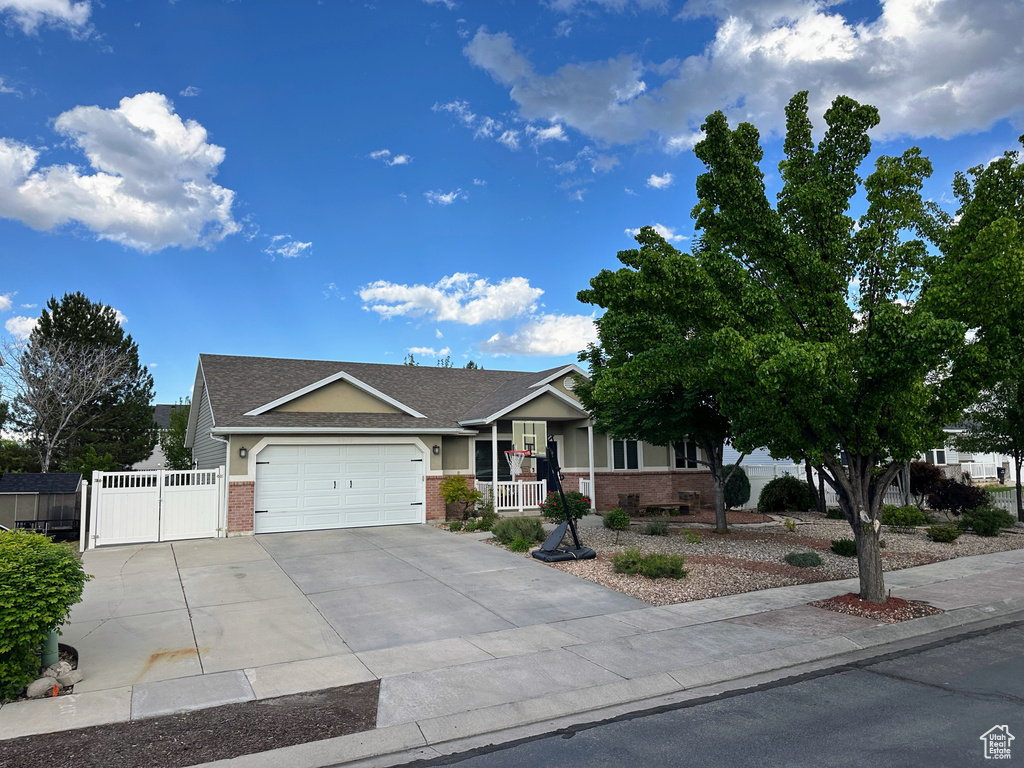 Ranch-style home with brick siding, an attached garage, concrete driveway, a gate, and a porch