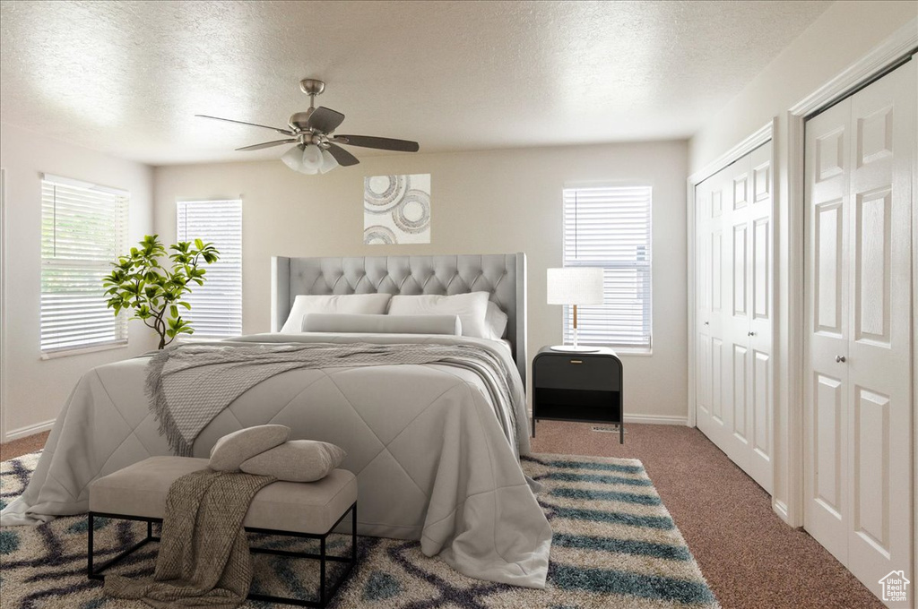 Bedroom with multiple closets, a textured ceiling, baseboards, carpet flooring, and multiple windows