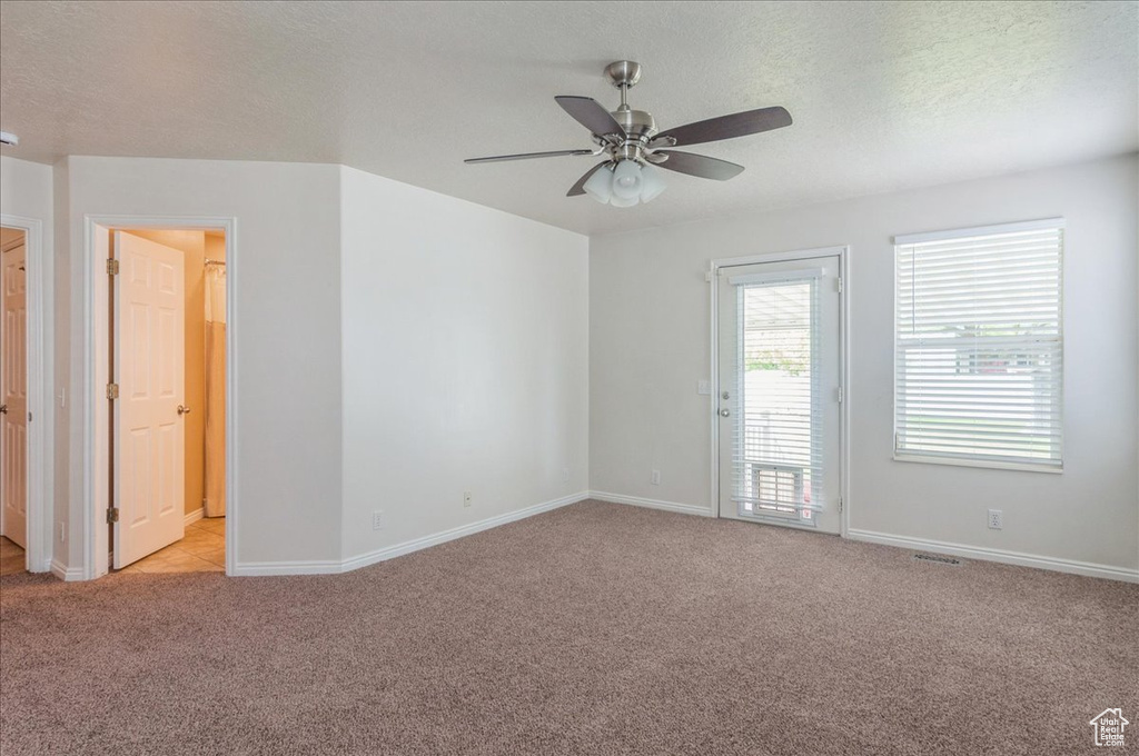 Empty room with light colored carpet, a ceiling fan, baseboards, and a textured ceiling