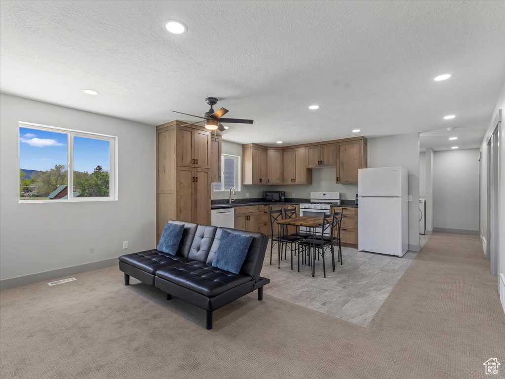 Living room with recessed lighting, baseboards, ceiling fan, washer / dryer, and light colored carpet