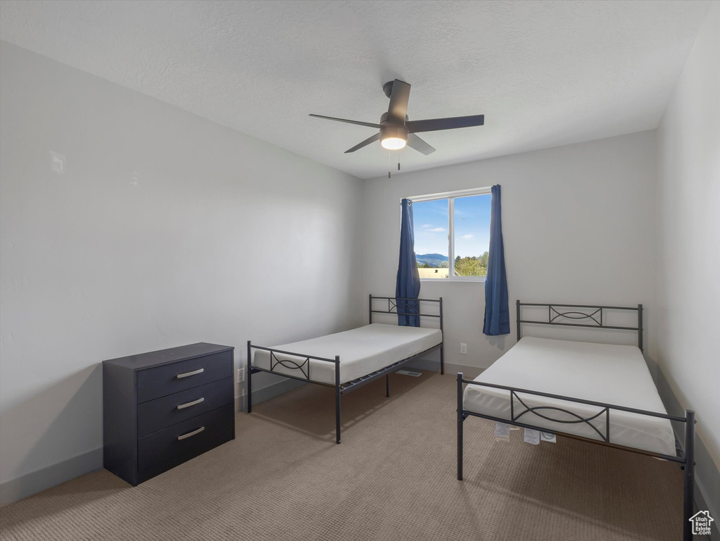 Bedroom with light colored carpet, baseboards, and ceiling fan