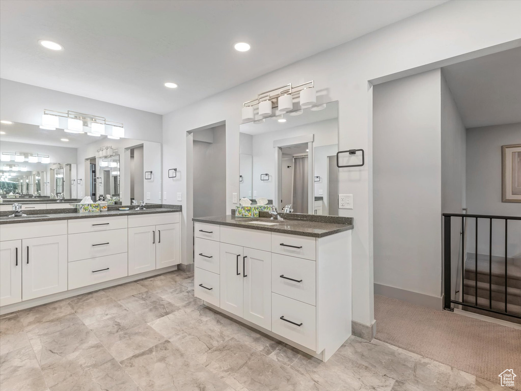 Full bathroom with recessed lighting, two vanities, and baseboards