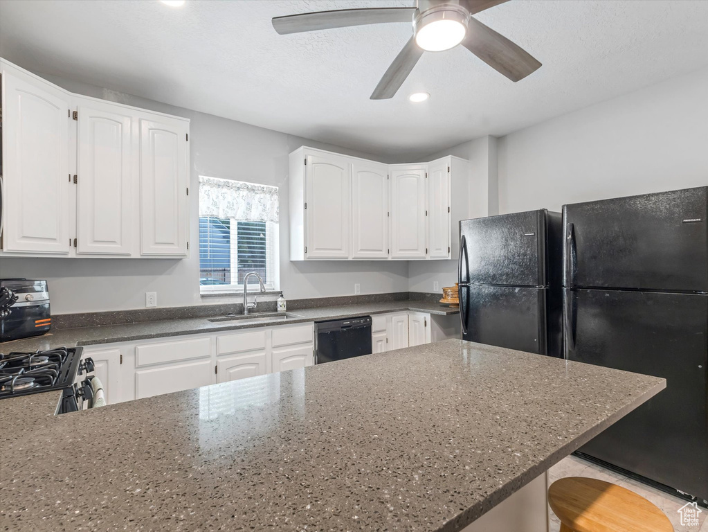 Kitchen with a sink, black appliances, white cabinets, a peninsula, and recessed lighting