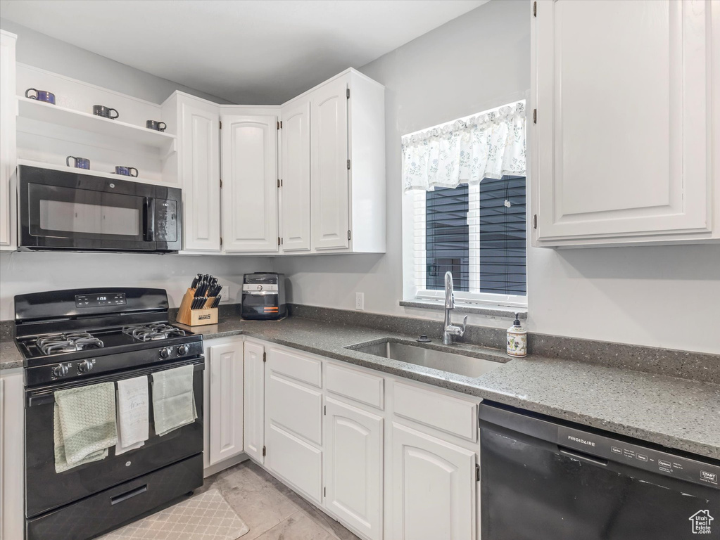 Kitchen with black appliances, a sink, white cabinets, open shelves, and dark stone countertops