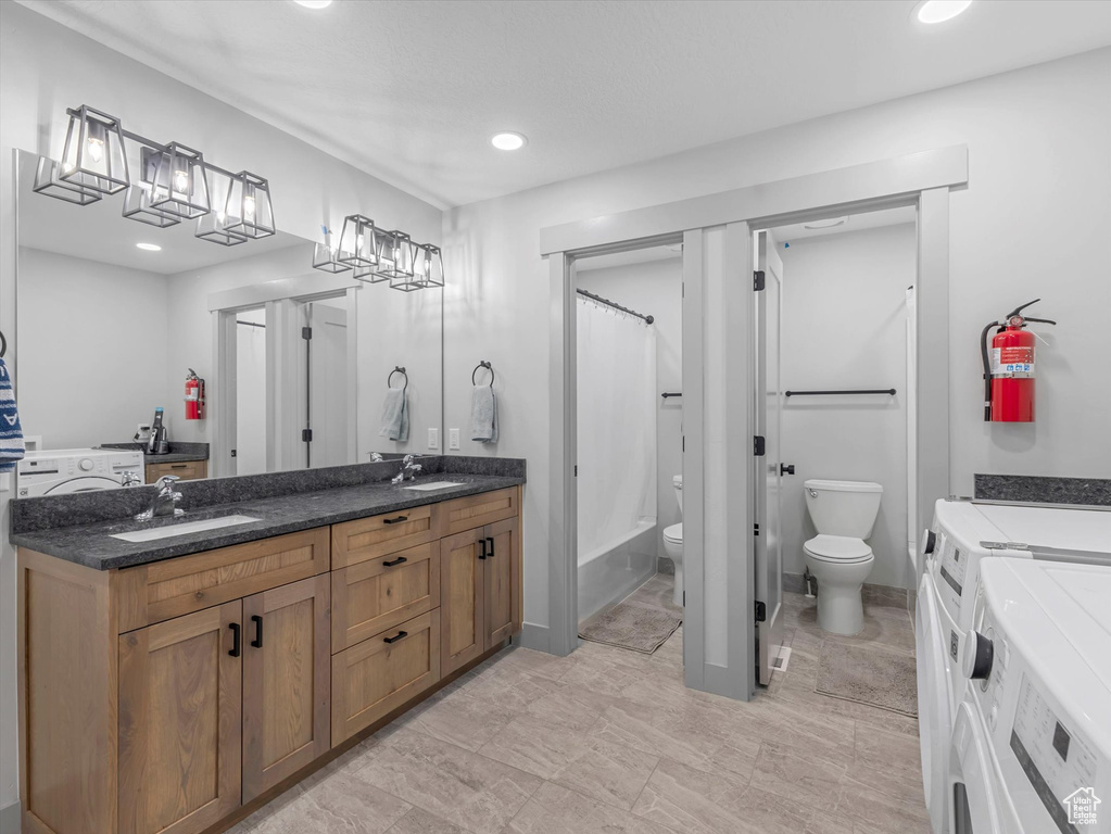 Full bathroom featuring separate washer and dryer, toilet, double vanity, and recessed lighting