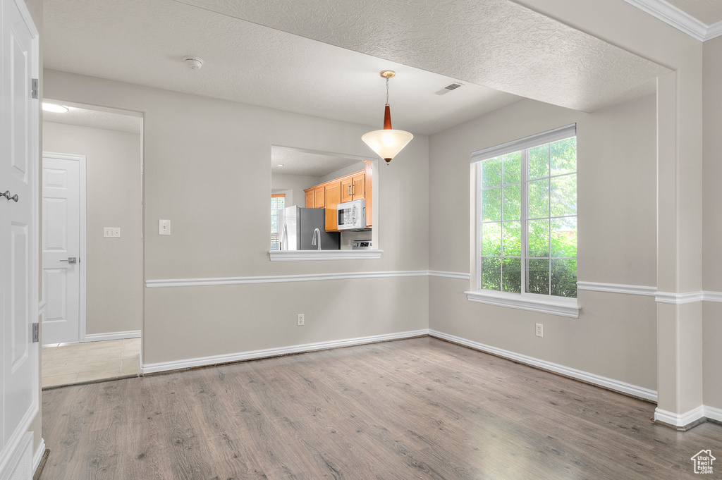 Unfurnished dining area featuring wood finished floors, plenty of natural light, and baseboards