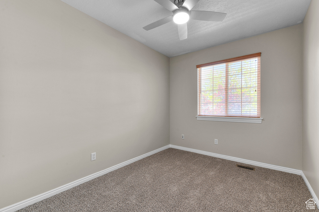 Carpeted empty room with ceiling fan and baseboards