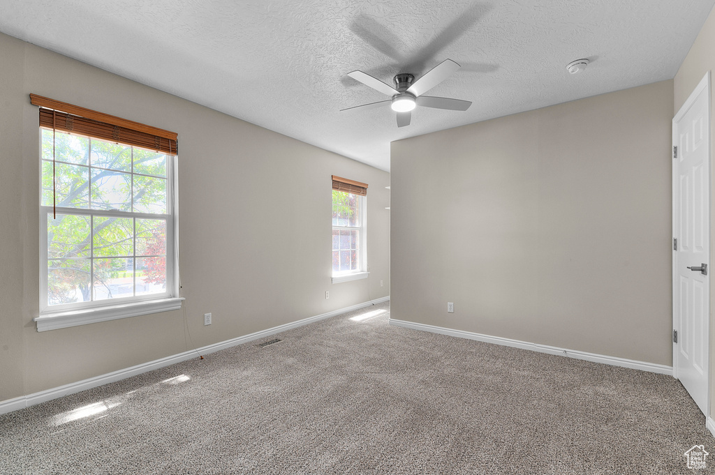 Carpeted spare room with ceiling fan, a textured ceiling, baseboards, and a smoke detector