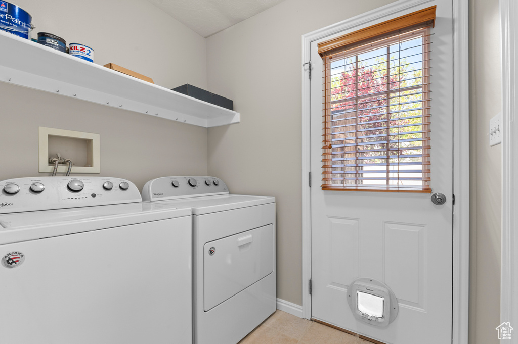 Laundry area with independent washer and dryer, plenty of natural light, light tile patterned floors, and baseboards