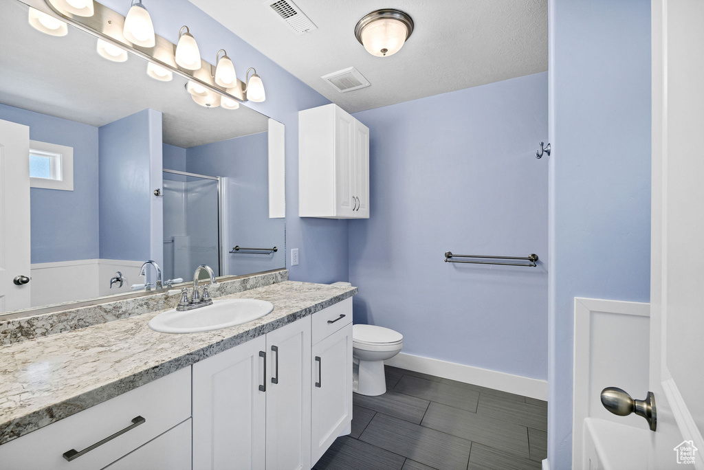 Full bathroom with a stall shower, vanity, toilet, and baseboards