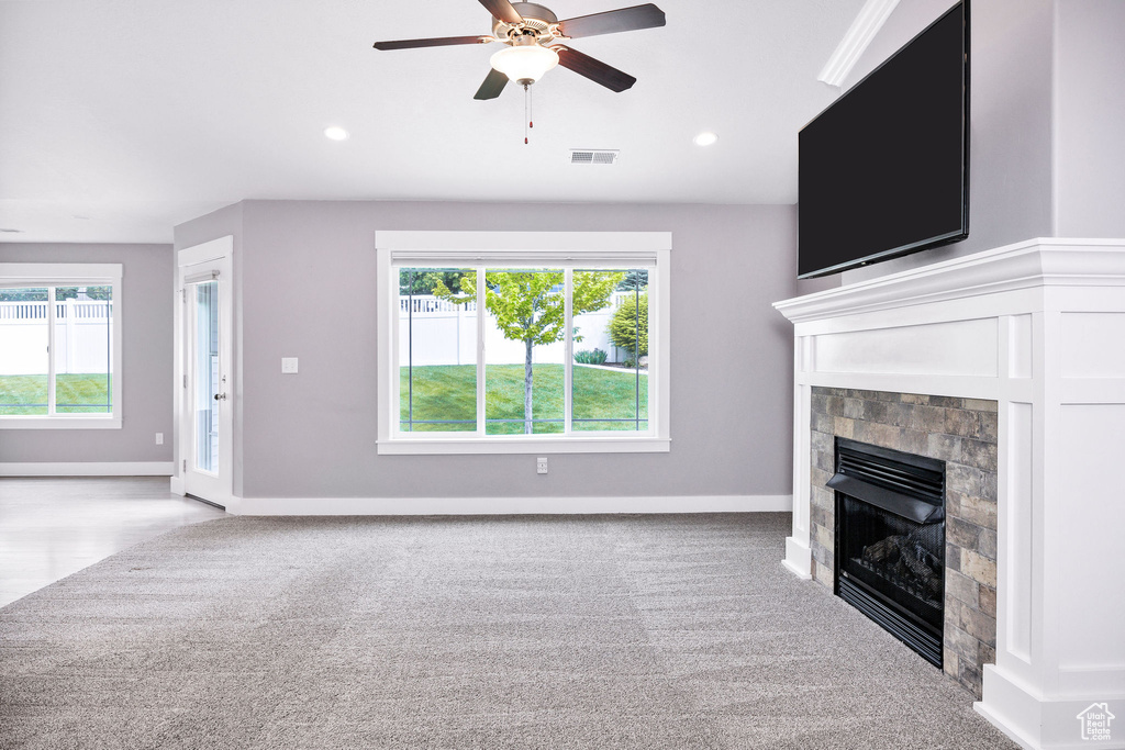 Unfurnished living room featuring a glass covered fireplace, ceiling fan, carpet, baseboards, and recessed lighting