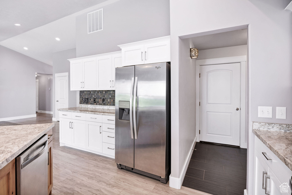 Kitchen featuring stainless steel appliances, baseboards, tasteful backsplash, light wood-type flooring, and recessed lighting