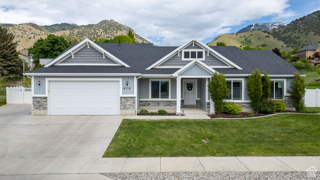 Craftsman-style house featuring stone siding, a mountain view, driveway, and a garage