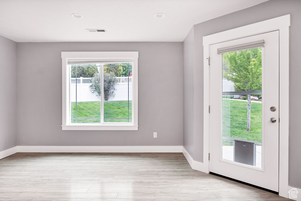Doorway with baseboards and light wood-style flooring