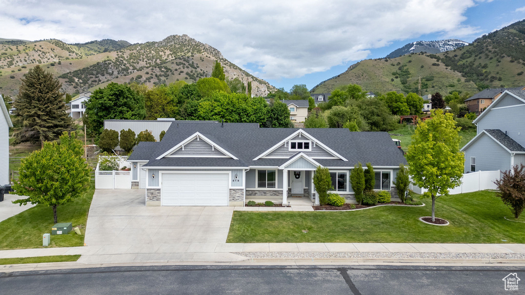 View of front of home featuring an attached garage, concrete driveway, stone siding, and a mountain view