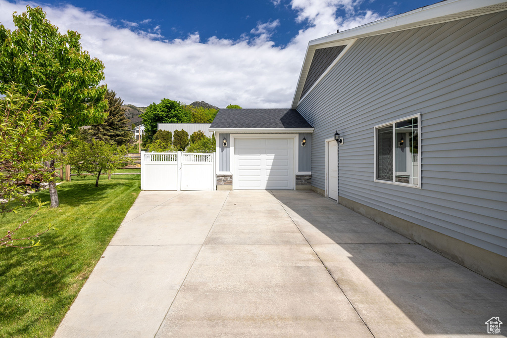 View of side of home featuring a gate, driveway, and a garage