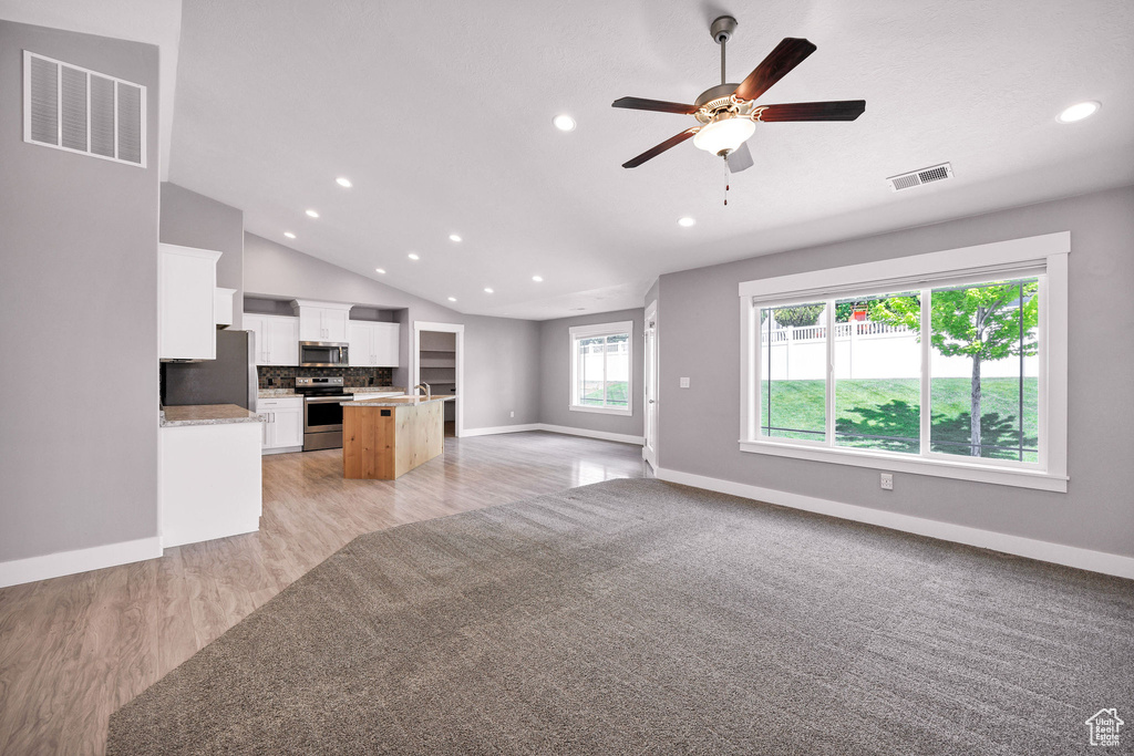 Unfurnished living room with recessed lighting, baseboards, ceiling fan, light wood finished floors, and vaulted ceiling