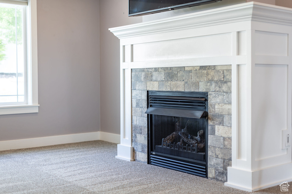 Detailed view of carpet floors, a fireplace, and baseboards