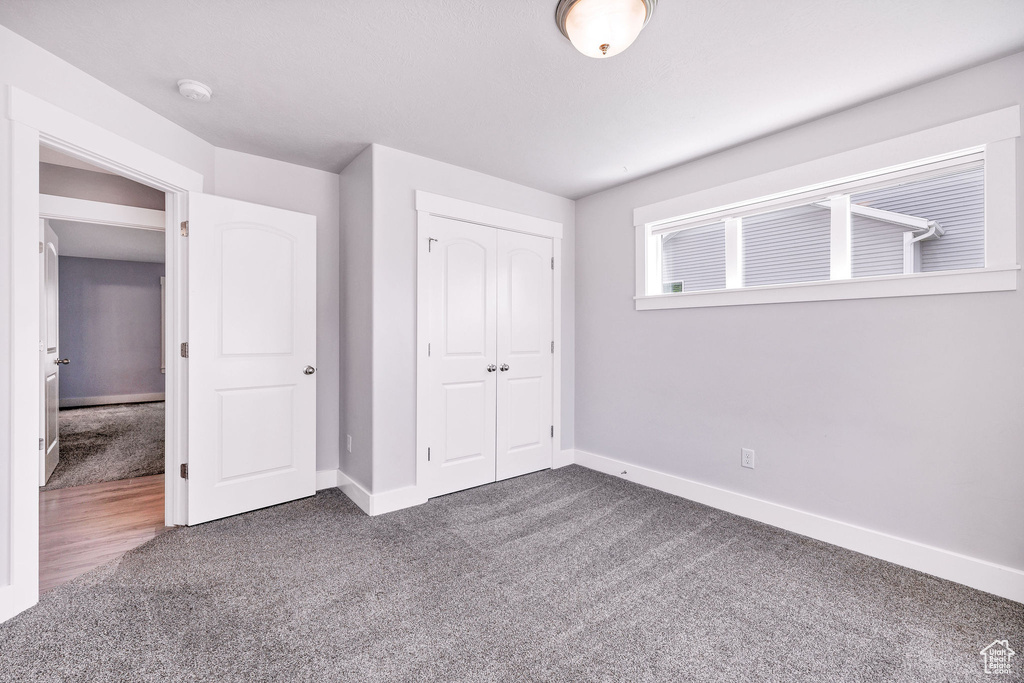 Unfurnished bedroom featuring carpet floors, baseboards, and a closet
