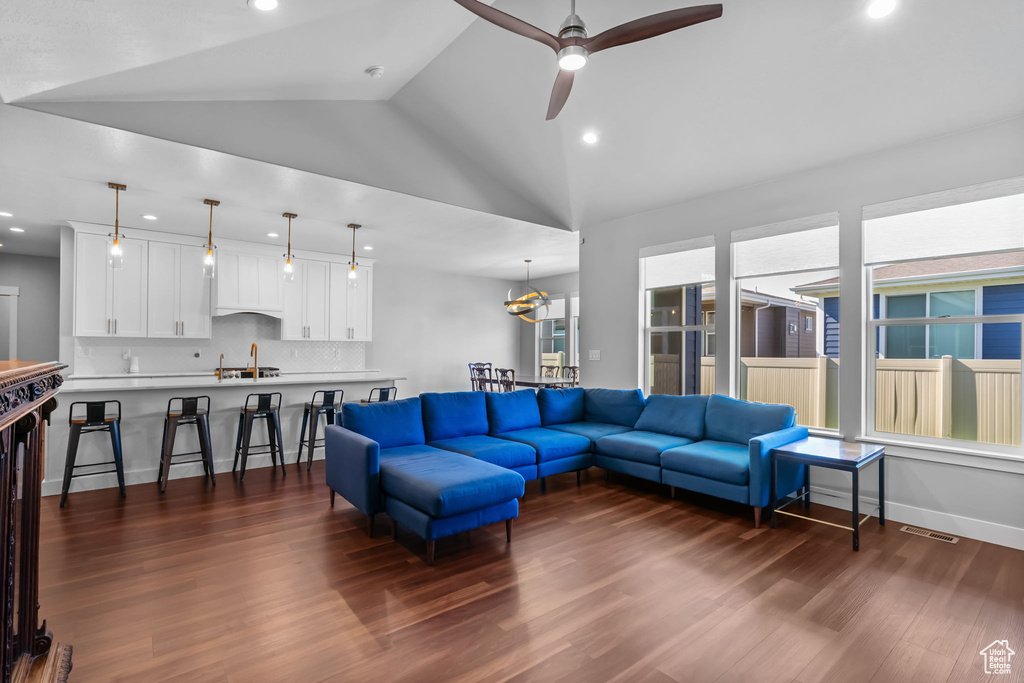 Living room with dark wood-type flooring, recessed lighting, lofted ceiling, and ceiling fan
