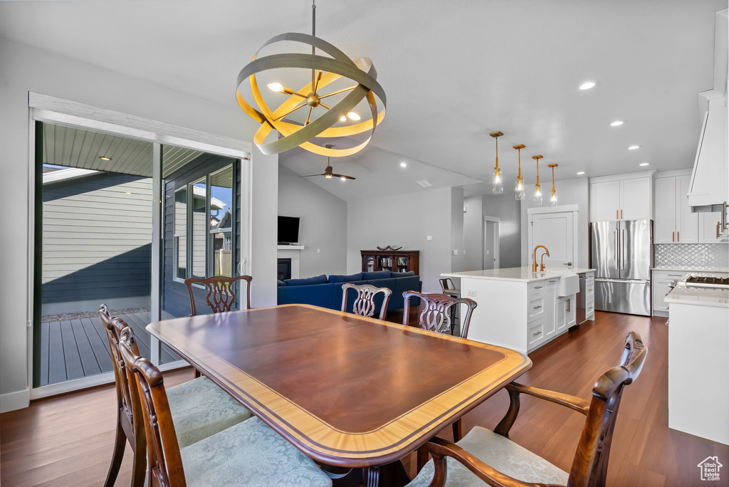 Dining space featuring a ceiling fan, a fireplace, dark wood finished floors, recessed lighting, and a chandelier