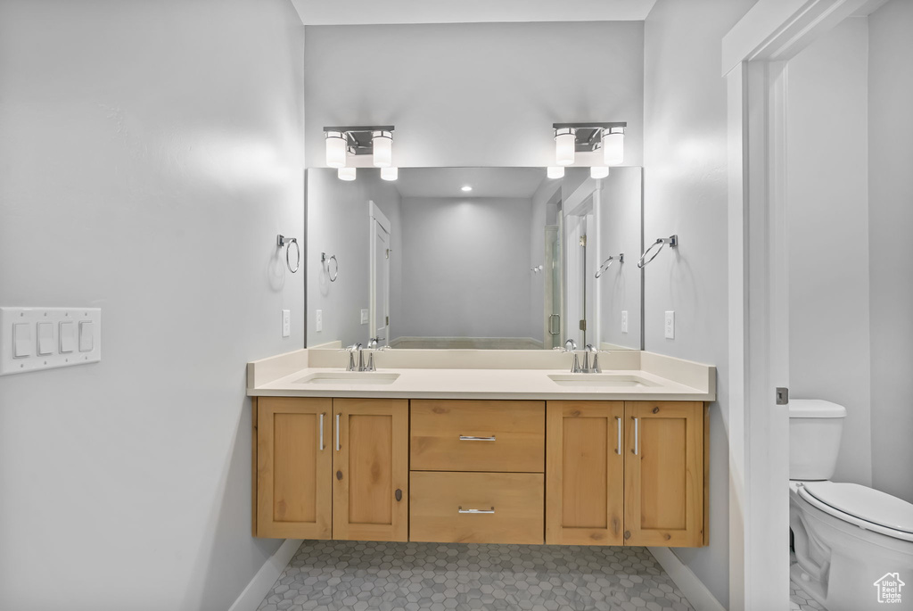 Bathroom with baseboards, toilet, double vanity, and tile patterned flooring