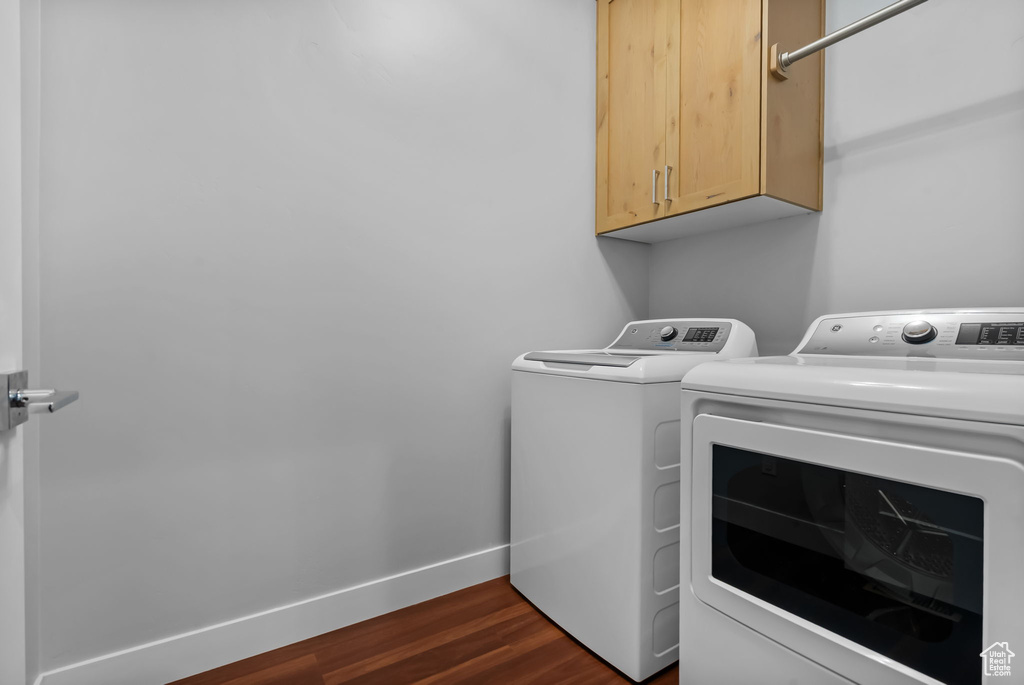 Laundry room with separate washer and dryer, cabinet space, dark wood-style flooring, and baseboards