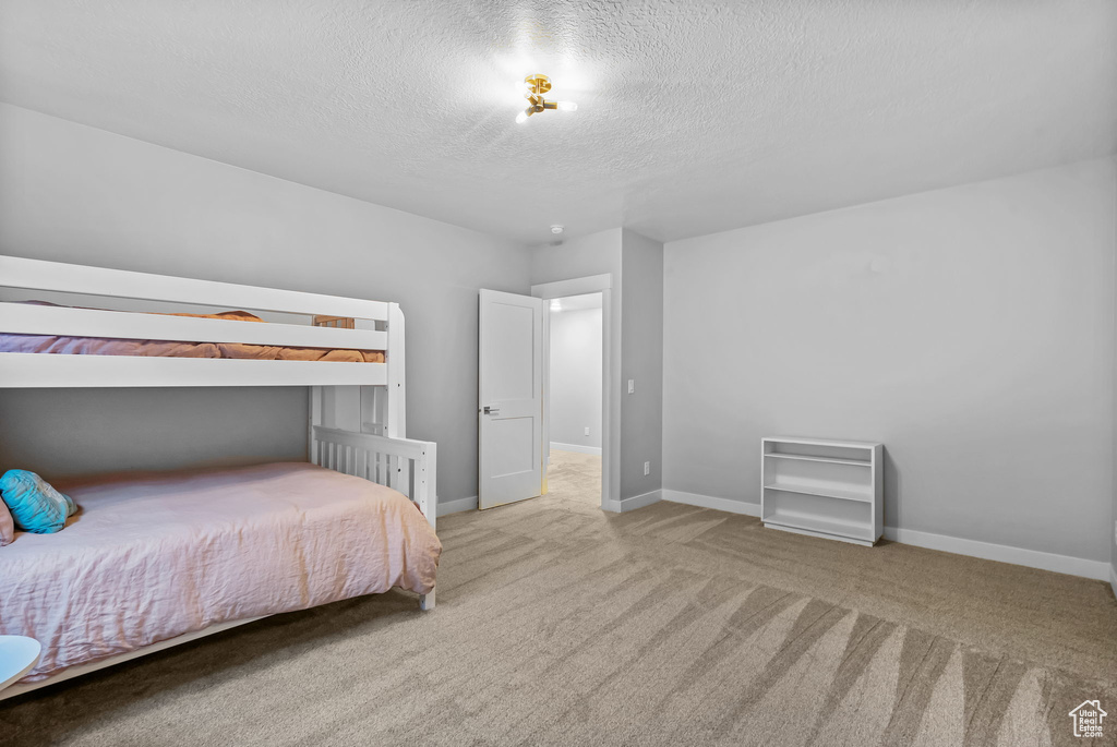 Carpeted bedroom with a textured ceiling and baseboards