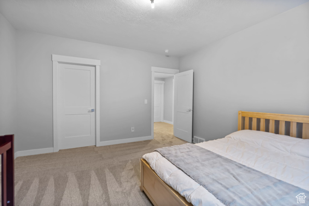 Bedroom with carpet flooring, baseboards, and a textured ceiling