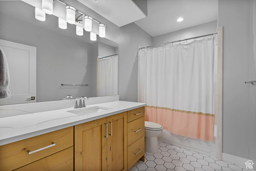 Bathroom with toilet, tile patterned flooring, vanity, and shower / bath combination with curtain