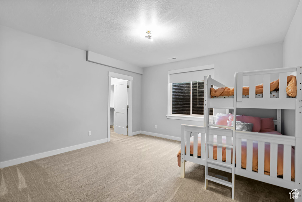 Bedroom featuring carpet floors, a textured ceiling, and baseboards