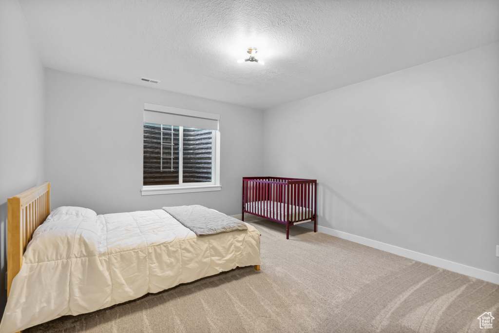 Carpeted bedroom featuring a textured ceiling and baseboards