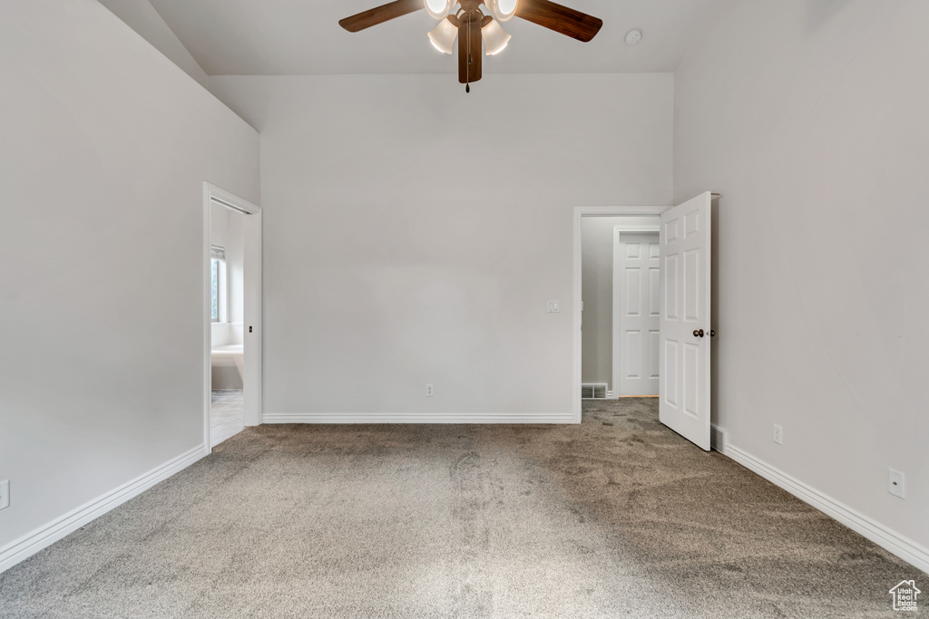 Carpeted empty room with ceiling fan and baseboards