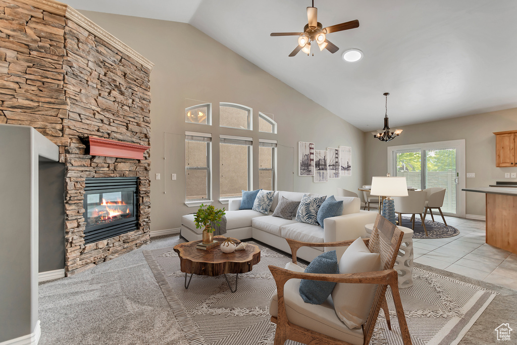 Living room featuring a fireplace, a chandelier, a ceiling fan, baseboards, and high vaulted ceiling