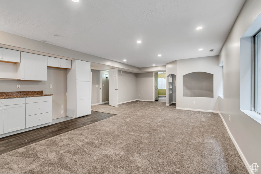 Unfurnished living room featuring carpet, baseboards, and recessed lighting