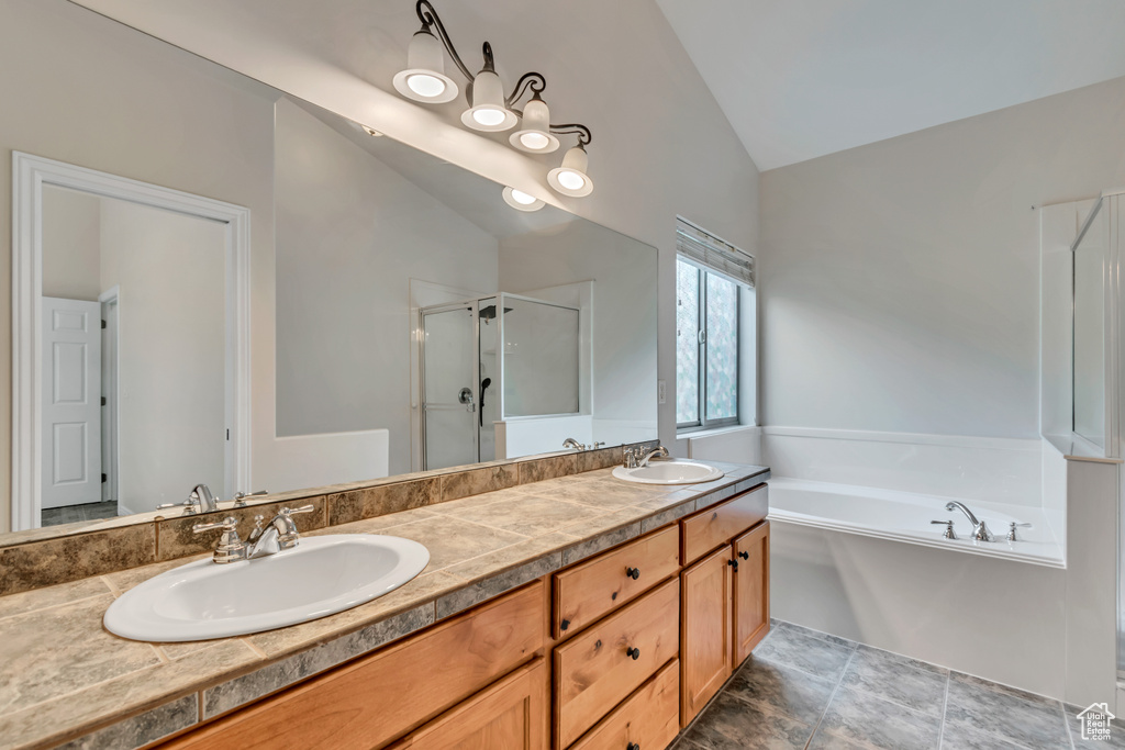 Full bathroom featuring vaulted ceiling, a stall shower, a bath, and double vanity