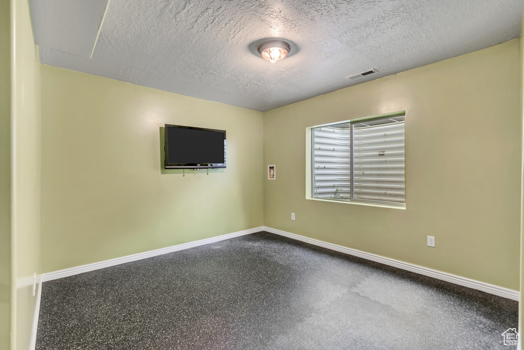 Unfurnished room featuring baseboards, a textured ceiling, and speckled floor