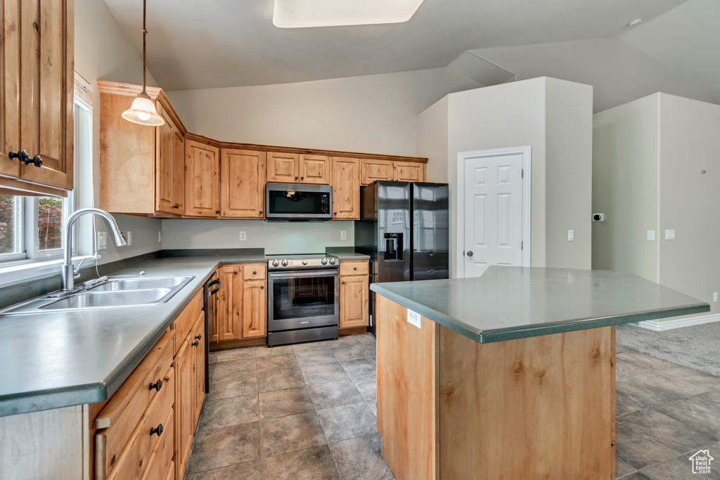 Kitchen with stainless steel appliances, a sink, lofted ceiling, pendant lighting, and stone finish flooring