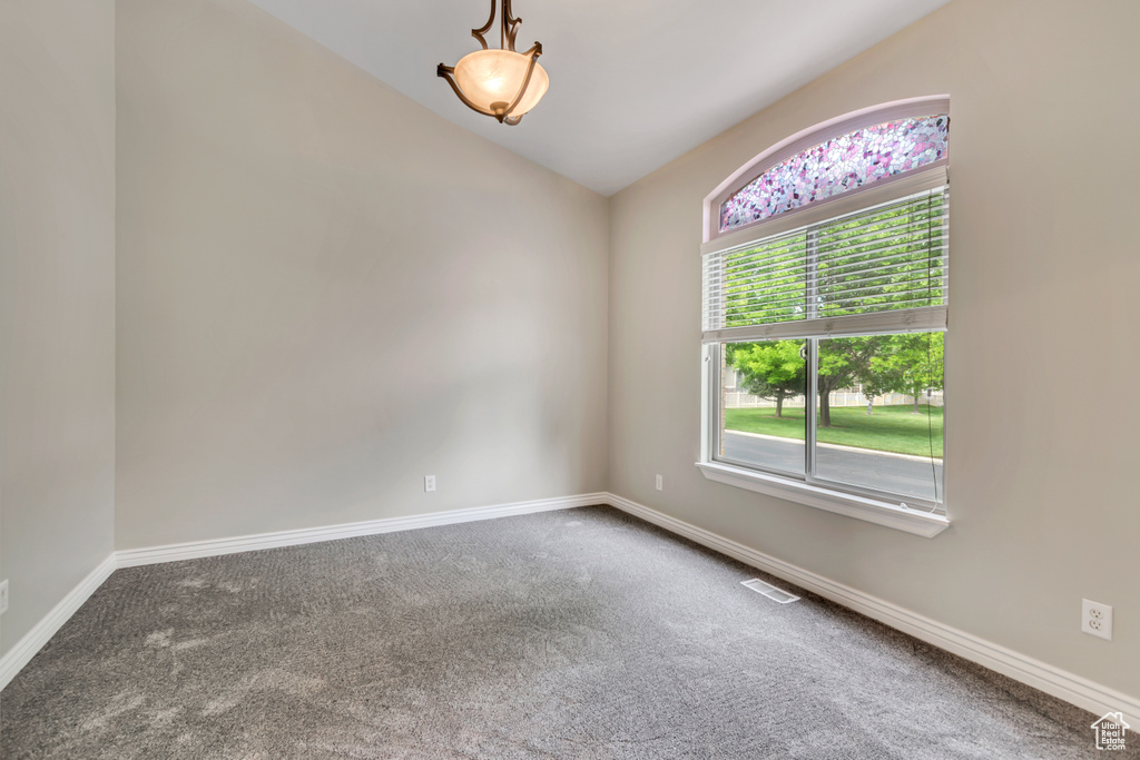 Unfurnished room featuring carpet flooring, lofted ceiling, and baseboards