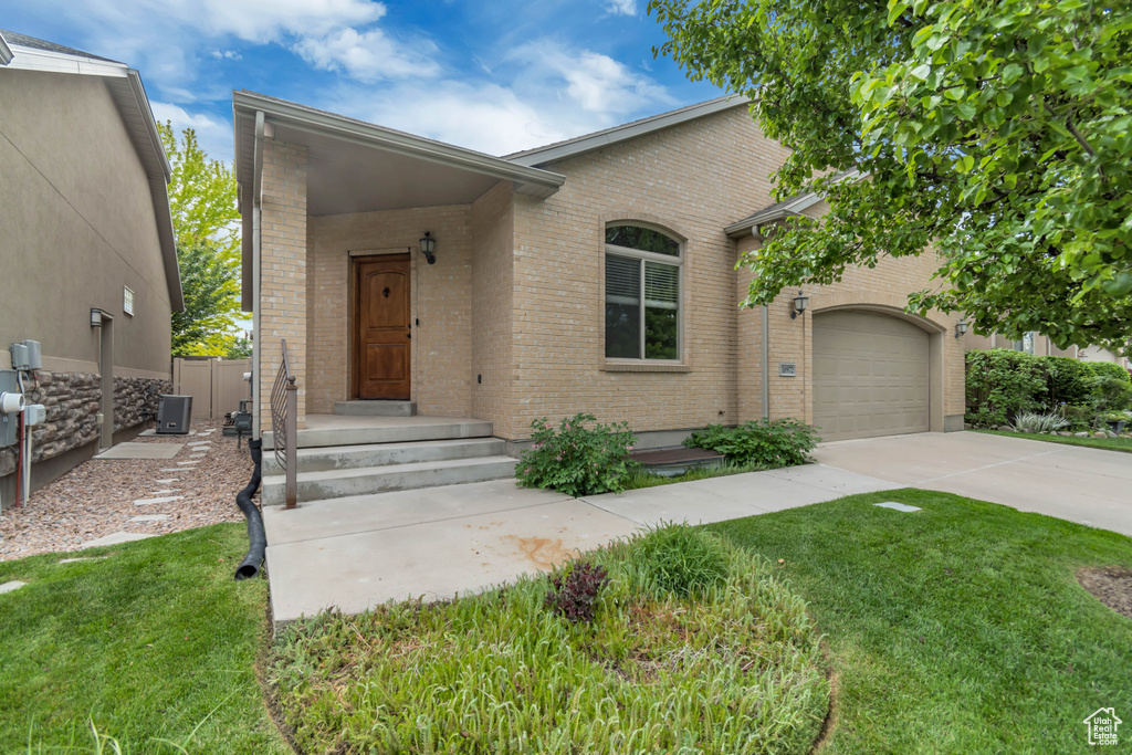 View of front of home featuring brick siding, driveway, an attached garage, and a front yard