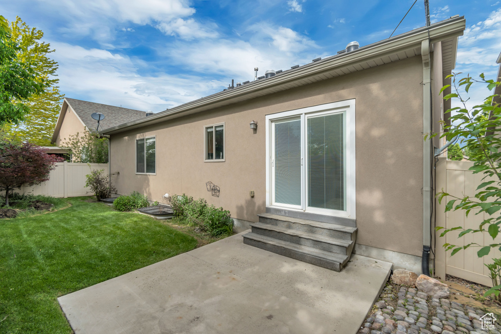 Rear view of house with entry steps, a patio area, and stucco siding