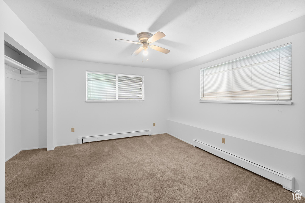 Unfurnished bedroom with baseboard heating, carpet floors, ceiling fan, and a closet