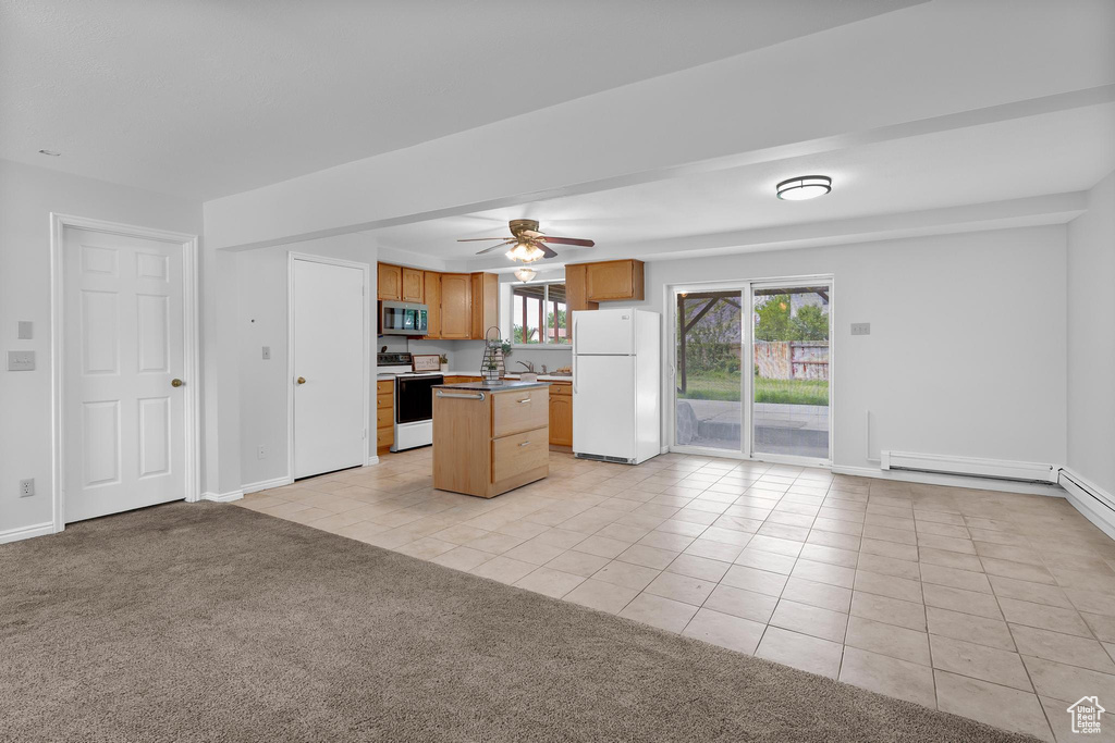 Kitchen featuring white appliances, light tile patterned floors, open floor plan, a kitchen island, and ceiling fan