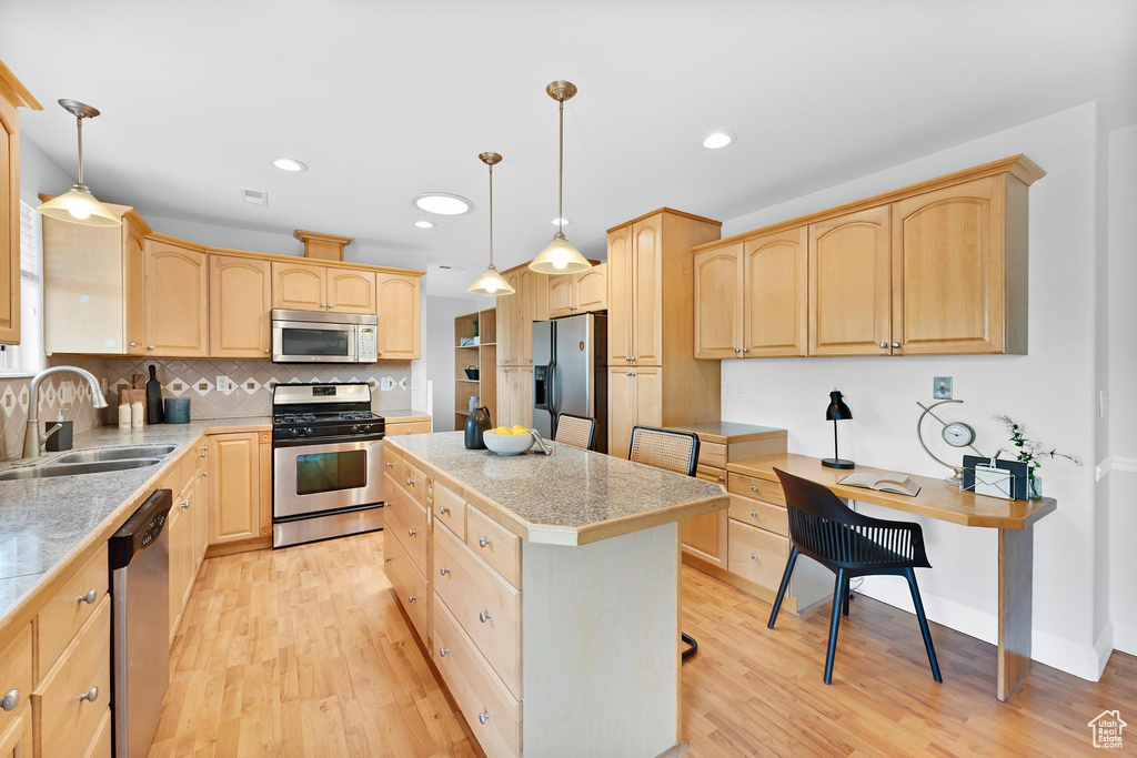 Kitchen featuring stainless steel appliances, a sink, light brown cabinets, tile counters, and a kitchen island